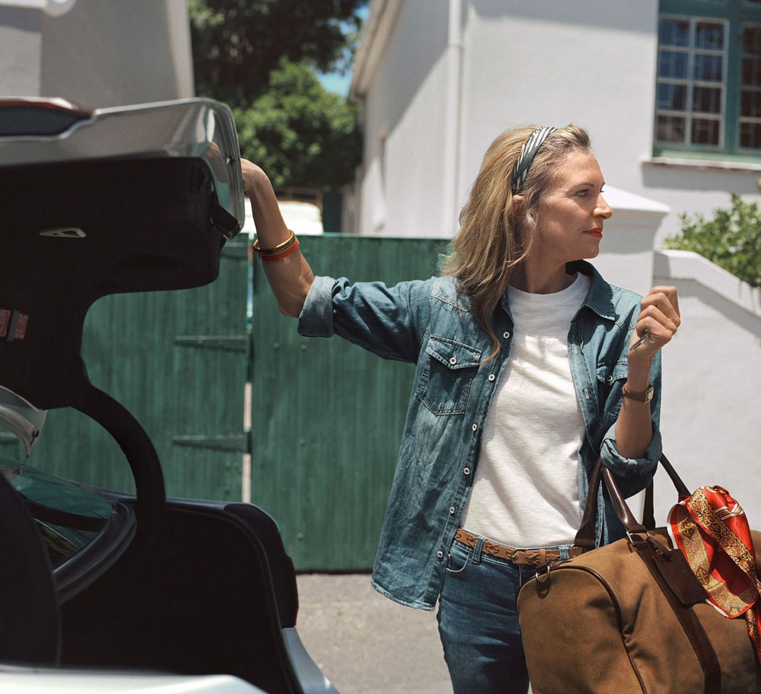 Lady with blonde hair opening the boot of a car